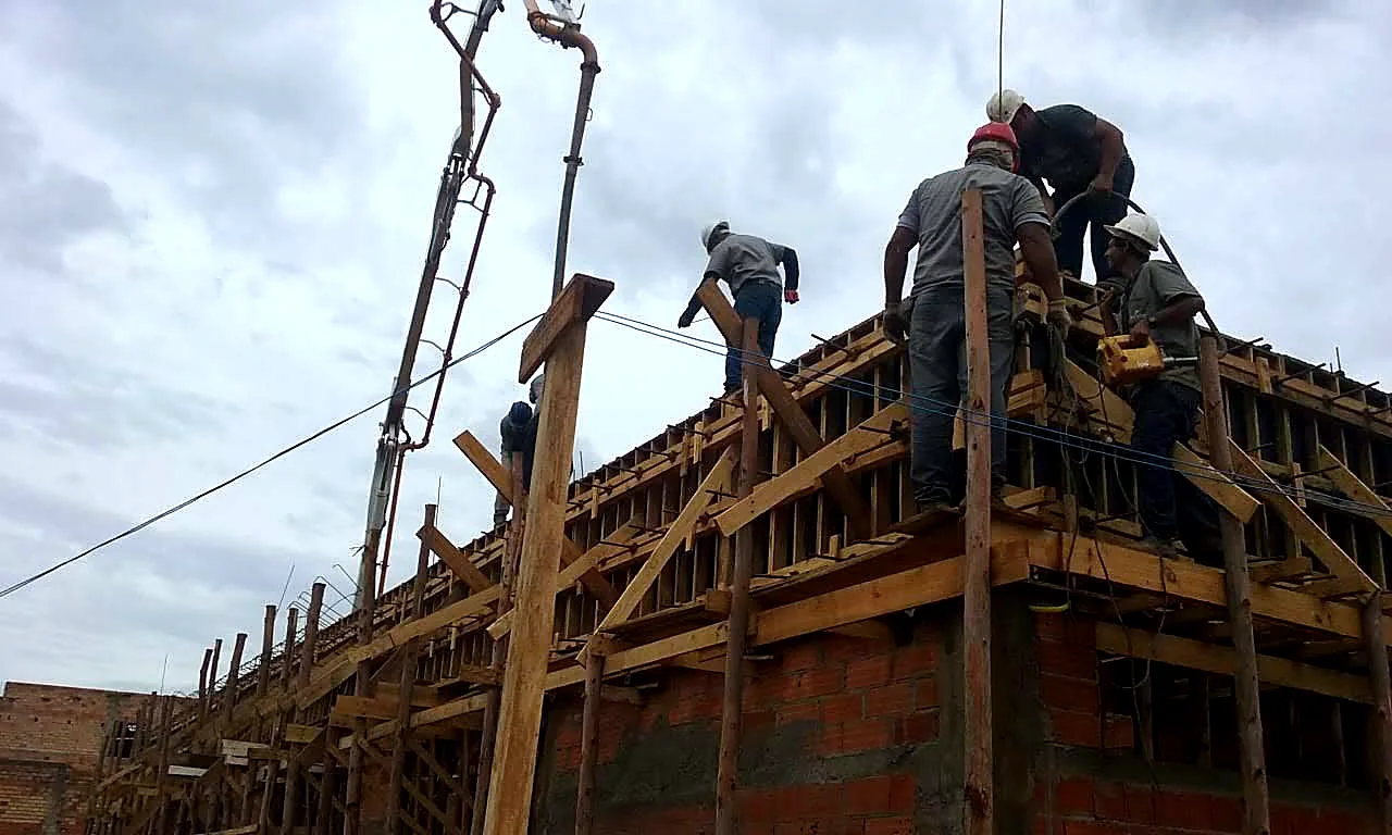 Equipe executando concretagem bombeada de viga estrutural com lançamento por bomba lança