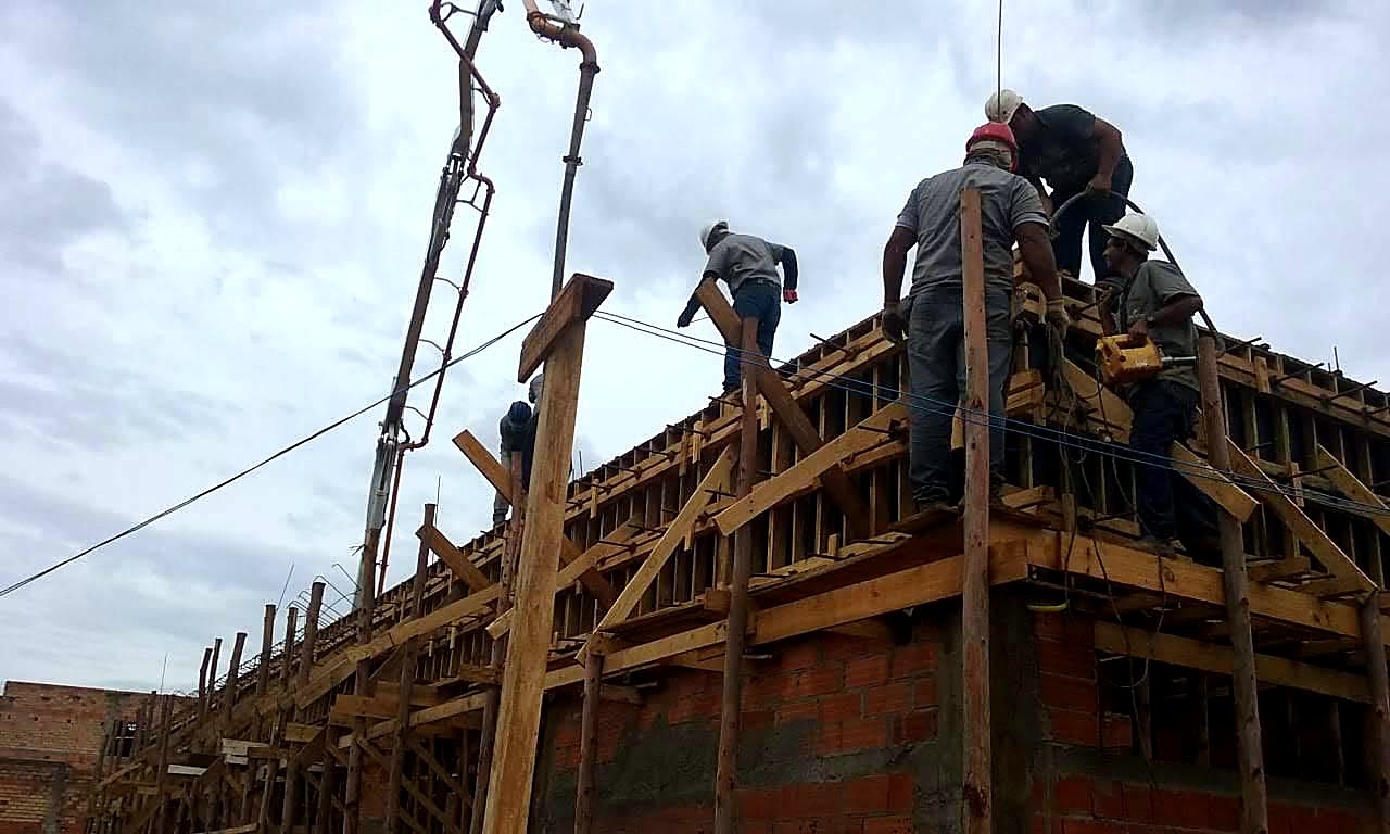 Equipe executando concretagem bombeada de viga estrutural com lançamento por bomba lança