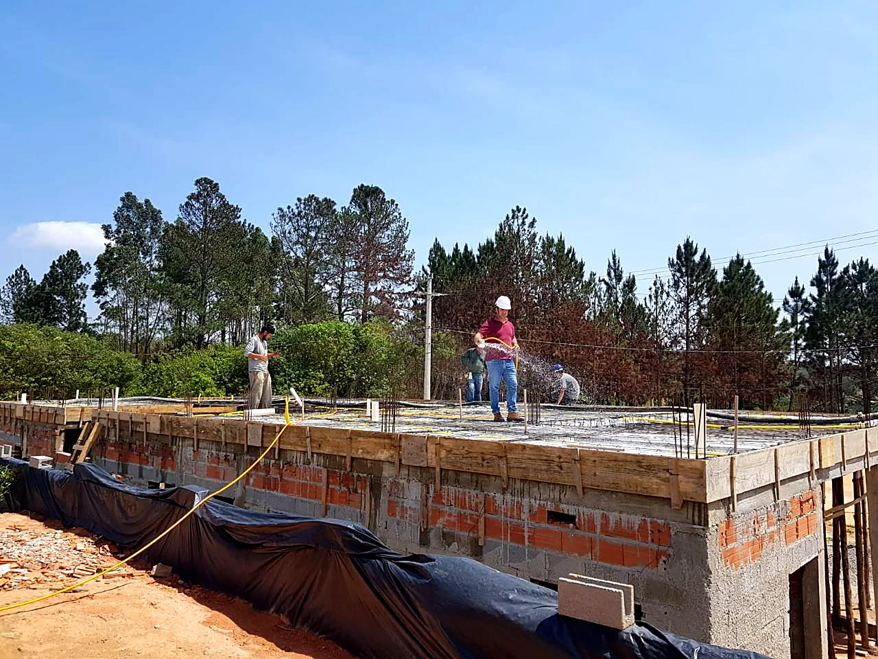 Equipe finalizando concretagem de laje de cobertura em residência Equipe finalizando concretagem de laje de cobertura em residência